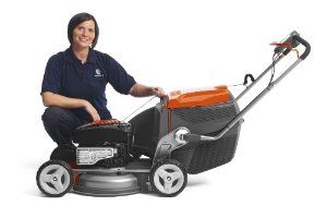 lady kneeling by a push lawn mover